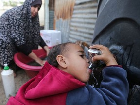 A Palestinian child drinks water from a public tap in the southern Gaza Strip on March 21, 2021.