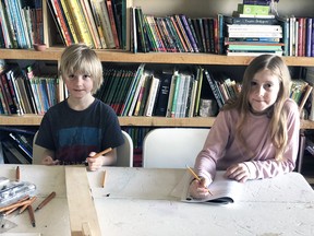 Logan Lealess (left) and sister Kayla are captured doing some school work at their home farm outside Fullarton. Logan is doing math while Kayla is writing out an Edward Lear poem in cursive writing. SUBMITTED