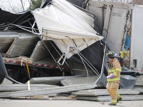 A firefighter looks at damage to two transport trucks that came into collision on March 23, 2021, on Highway 402 near Christina Street in Sarnia.  Drivers of both trucks were taken to hospital and a section of the westbound highway was closed.