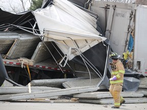 A firefighter looks at damage to two transport trucks that came into collision Tuesday on Highway 402 near Christina Street in Sarnia. Drivers of both trucks were taken to hospital and a section of the westbound highway was closed.