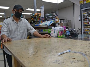 Sandeep Kaleka, co-owner of Century Convenience in Spruce Grove, stands next to a wooden platform that was installed at the store a year ago to help with physical distancing during the pandemic. Regular customers and visitors to the store have signed the platform as a way to remember world events including the Black Lives Matter movement and the Covid-19 pandemic.