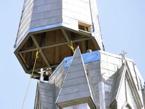 On-site workers guide a 40-foot piece, complete with a seven-foot cross, on the steeple of St. Patrick's Church in Kinkora March 24. It's been 17 1/2 years since the steeple has been in place, a landmark for miles around that parishioners say makes the Catholic church complete once again. ANDY BADER/MITCHELL ADVOCATE