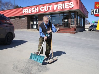 Tim Zografopoulos, of Deluxe on Regent Street in Sudbury, Ont., cleans up the parking lot area. Today's forecast says there a 100 per cent chance of rain. John Lappa/Sudbury Star/Postmedia Network