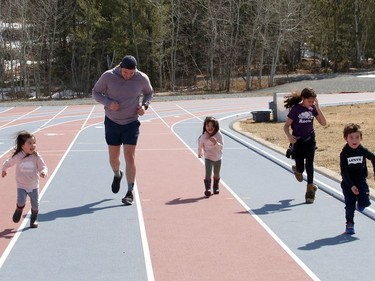 Zach Innes jogs with his children, Bailey, left, Ava, Kaycee and Logan at the track located at Laurentian University in Sudbury, Ont. on Monday March 22, 2021. John Lappa/Sudbury Star/Postmedia Network