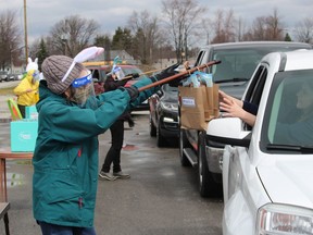 Davida Nimmo passes treat bags during a drive-by Easter event the Optimist Club of Moore held March 28 in the parking lot at the Courtright Community Centre. Paul Morden/Postmedia Network