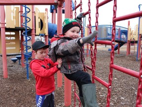 Liam Charette, 8, helps his younger brother Hayden, 5, climb a play structure at Hollinger Park on Thursday. They were taking advantage of a break in the recent wet weather Timmins has been having. Over the next few days, temperatures will be hovering around the freezing point with some periods of snow expected.

RICHA BHOSALE/The Daily Press
