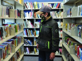 Dominic Peters, 12, checks out some books last Thursday at the Champion Municipal Library. The Albeta government announced March 1 that the libraries could reopen, but must limit capacity to 15 per cent of fire code occupancy. STEPHEN TIPPER