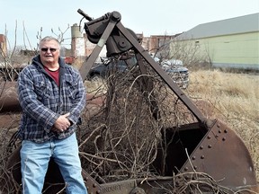 Terry Hill standing by an Industrial Brownhoist clamshell bucket that his father guided through the grit and industrial grind and hum of "the Sugar factory." In the background, the remains of "the Sugar factory." At the right of the photo are the riverside freight sheds, standing in the same location and configuration as they have since 1901. Photo submitted by Terry Hill.