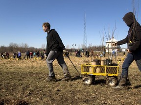 Kyle Lycett and Autumn Hull, both of East Elgin haul a wagon load of small trees and shrubs out to where their classmates were planting. They were among over 600 students planting native trees and shrubs in parkland near Dingman Drive and Wonderland Road in in this photo from 2016. File  photo/Postmedia Network