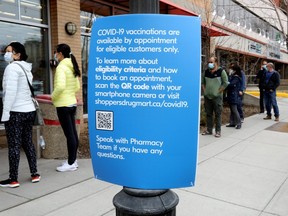 Patrons wait outside of the Shoppers Drug Mart in Kensington as they are taking appointments for COVID vaccines in Calgary on Wednesday, March 24, 2021.