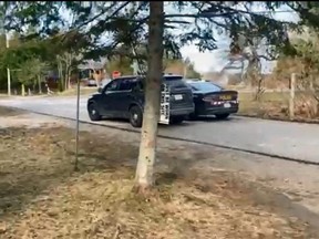 Police vehicles sit near a Tobermory home where a man says shots were fired on March 31. (Screen grab of submitted video)