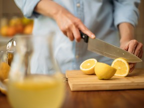 Pitcher with lemonade and woman cutting lemons