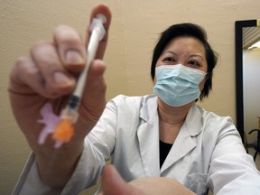 Pharmacist Joanna Wong administers a COVID-19 vaccine to a patient at Market Drugs Medical pharmacy in Edmonton on Tuesday April 13, 2021.