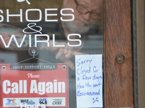 Ron Cole puts a sign in the door of Pretty Woman's Shoes and Swirls in downtown Owen Sound on the morning of Thursday, April 15, 2021, after the Grey Bruce Health Unit declared a “critical threshold” due to a surge in COVID-19 cases and a need to trace close contacts. Everyone was being asked to stay home except for essential reasons. OB GOWAN