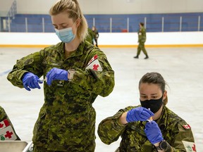 Lt. Samantha O'Keefe (left) and Cpl. Carole-Anne Laroche, both from 1 Canadian Field Hospital, prepare to administer vaccinations to Garrison Petawawa Canadian Armed Forces members.