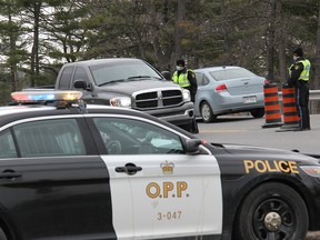 Upper Ottawa Valley OPP officers ask a driver what their reason is for seeking to enter Ontario at the interprovincial border on Highway 148 near Pembroke on April 21. As of 12:01 a.m. Monday, April 19 the Ontario government closed its borders with Quebec and Manitoba in order to help prevent the spread of COVID-19 and its variants.