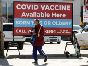 A pedestrian walks past a sign advertising COVID-19 vaccines at the Shoppers Drug Mart, 8065 104 St., in Edmonton Wednesday April 21, 2021.