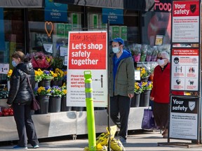 Shoppers maintain their distance as they walk along a sidewalk in Toronto on April 8, 2021, the day a province-wide stay-at-home order went into effect.