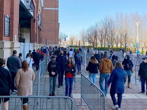 People line up at M&T Bank Stadium in Baltimore, Maryland, which was transformed in a COVID-19 mass vaccination site on March 20, 2021. (Photo by Eric BARADAT / AFP)