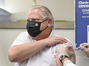 Ontario Premier Doug Ford, left, receives the Astrazeneca-Oxford COVID-19 vaccine from pharmacist Anmol Soor at Shoppers Drug Mart during the COVID-19 pandemic in Toronto on Friday, April 9, 2021. THE CANADIAN PRESS/Nathan Denette ORG XMIT: NSD103
