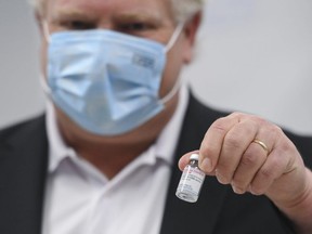 Ontario Premier Doug Ford holds a vial of the Moderna COVID-19 vaccine as frontline workers at Apotex are administered COVID-19 vaccinations through a mobile clinic set up by Humber River Hospital on Friday, April 9, 2021.