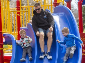 Mark Hartery takes in a slide with his sons Owen, 2, and Zachary 4, at the Springbank Park playground on Tuesday March 30, 2021. Premier Doug Ford said Saturday the provincial government will amend new restrictions announced Friday to allow playgrounds to stay open. Mike Hensen/The London Free Press/Postmedia Network