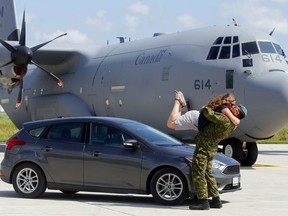 Sarah Heino takes to the air while kissing her husband, Cpl. Julian Tutino, Aug. 26 at the first Rubber on the Ramp United Way fundraiser at CFB Trenton. It allowed citizens to be photographed with their vehicles next to military aircraft - in this case a CC-130 Hercules transport. It garnered photographer Luke Hendry a mention as a finalist in the 2020 Ontario Newspaper Awards, announced Friday, for feature photography in newspapers with circulations of less than 25,000.