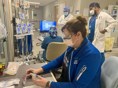 Monica Hewitson, a registered nurse in the critical care ward of Brantford General Hospital prepares some medication, while Dr. Abayomi Ajayi, medical director of critical care (centre) and Dr. Damien Medina (right) follow up on a patient. Vincent Ball/Brantford Expositor/Postmedia Network