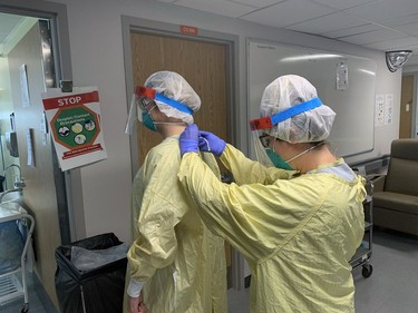 Jennifer Brown, a registered nurse in the critical care ward of Brantford General Hospital, ties the protective gown of her colleague, Celine Bosse, also a registered nurse, before entering a COVID-19 patient's room. Vincent Ball