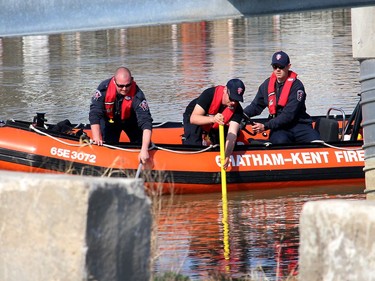Chatham-Kent firefighters, from left, Ben Fisher, Dave Stallaert and James Labombard, use poles to feel around the bottom of the Sydenham River near the foot bridge in Wallaceburg, Ont. in the area where a body was recovered on Wednesday April 7, 2021. Ellwood Shreve/Chatham Daily News/Postmedia Network