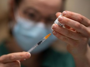 A pharmacist prepares a dose of the AstraZeneca COVID-19 vaccine with a syringe. 
(LOIC VENANCE/AFP via Getty Images)