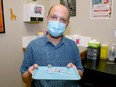 Pharmacist Jason Kmet holds a dose of AstraZeneca vaccine at the Polaris Travel Clinic and Pharmacy in Airdrie. Friday, April 9, 2021.