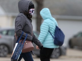 People wear masks while passing each other in the street to help prevent a third wave of COVID-19 infections. (file photo)