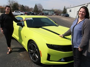 Jenna Steadman, left, county coordinator with Sarnia-Lambton Rebound, and Kristin MacFarlane, general manager of MacFarlane Chevrolet Buick GMC in Petrolia, stand with the 2021 Camaro being raffled off as a fundraiser for Rebound.