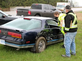 A Lambton OPP officer inspects a car involved in a three-vehicle crash at Forest Road and London Line on Thursday April 15, 2021 in Plympton-Wyoming, Ont.