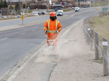Manny Castanheira, of the City of Greater Sudbury roads division, clears sand and gravel from a walking path on Regent Street on Thursday.