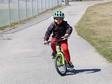 Jaden Rushton, 6, rides his bike with his grandmother at the Terry Fox Sports Complex in Sudbury, Ont. The weather for this weekend calls for rain on Saturday while it will be partially sunny on Sunday. John Lappa/Sudbury Star/Postmedia Network