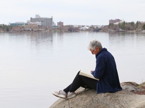 Joanne Proulx sits on a rock while journaling at Ramsey Lake in Sudbury, Ont. on Thursday April 29, 2021. John Lappa/Sudbury Star/Postmedia Network