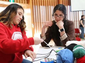 Maria Iotzov, left, and Nadia Verrelli participate in a finger-weaving workshop at a celebration of Metis history and culture at Laurentian University in Sudbury, Ont. on Friday March 16, 2018. Verrelli, a professor, was let go as Laurentian announced deep job and program cuts this week. John Lappa/Sudbury Star/Postmedia Network