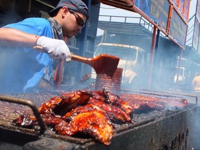 A rib vendor from 2014's Sarnia Kinsmen Ribfest bastes his ribs with a heaping of barbecue sauce. Due to COVID-19, the 22nd annual Ribfest will be a drive-thru affair taking place at Lambton College on Father's Day weekend. File photo/Postmedia Network