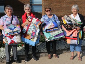 Millet Arts N' Crafts Guild members Clara Hampson, Vi Rudolph, Peggy Robinson, and Anne Clark taking quilts donated to the John A. Smith Manor.