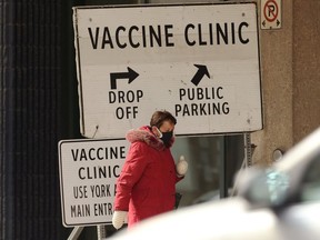 A woman who appears to be wearing two masks walks by the COVID-19 vaccination super site at RBC Convention Centre in Winnipeg on Sun., April 11, 2021.