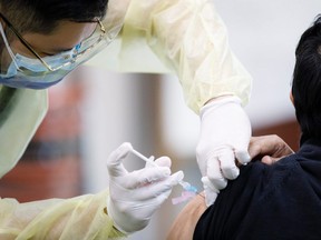 File: Healthcare workers administer COVID-19 vaccinations.