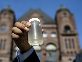 Kiiwetinoong MPP Sol Mamakwa holds up water collected from Neskantaga First Nation, where residents were evacuated over tainted water in October 2020, during a rally at Queen's Park in Toronto.