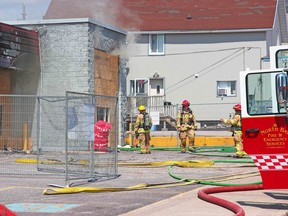 North Bay Fire and Emergency Services members tackle a fire at the downtown Midas at the corner of Main Street East and Fisher Street, Monday afternoon. It is the second fire to occur at the shop this year since Feb. 22. Michael Lee/The Nugget