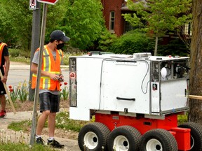 Two trained chaperones from Top Hat Robotics accompany a sidewalk-inspection robot as it scans for cracks and other deficiencies in Stratford's sidewalks that could require future repair. (Galen Simmons/The Beacon Herald)