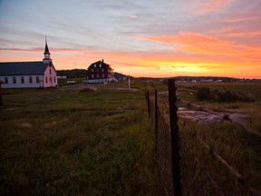 The sun rises near the site of the Holy Angels Residential School in Fort Chipewyan, which has since been destroyed, on August 26, 2010. The Nativity of the Blessed Virgin Roman Catholic Church and the rectory are seen in the background. Ryan Jackson/Postmedia Network