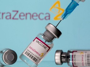 Vials labelled "AstraZeneca COVID-19 Coronavirus Vaccine" and a syringe are seen in front of a displayed AstraZeneca logo, in this illustration photo taken March 14, 2021.