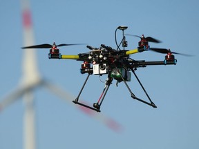 ZEESTOW, GERMANY - MAY 15:  A multirotor quadcopter drone used for aerial photography flies near a wind turbine in Germany.  The UCP government has grounded a proposal to use aerial drones to monitor campers and outdoor enthusiasts on public lands.