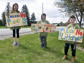 The DeBlock family on Line 46 in Logan Ward of West Perth, Payten (left), 8; Joel, 6 and Lucas, 10, display homemade signs they created and planned to erect along their farm and roadside to try and stop littering. "The kids were just fed up," mom Sheena said. ANDY BADER/MITCHELL ADVOCATE
